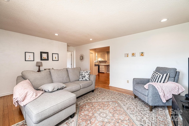 living area with a textured ceiling, wood finished floors, and recessed lighting