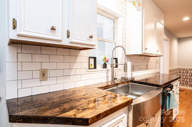 kitchen with dark stone counters, light wood-style flooring, white cabinetry, backsplash, and recessed lighting