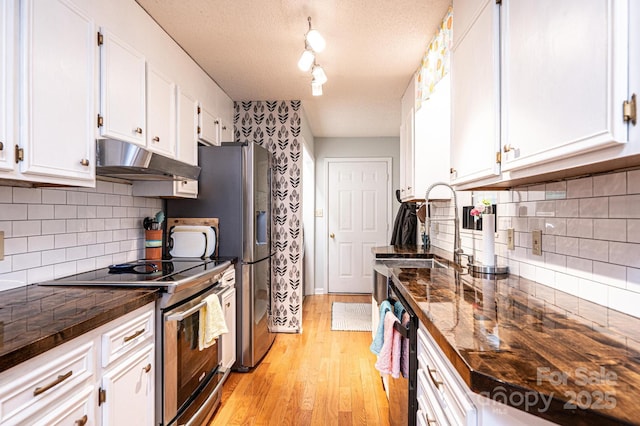 kitchen with under cabinet range hood, a sink, white cabinetry, light wood-type flooring, and stainless steel range with electric stovetop