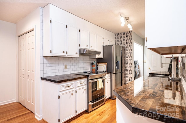 kitchen featuring dark countertops, light wood-style flooring, appliances with stainless steel finishes, white cabinets, and under cabinet range hood