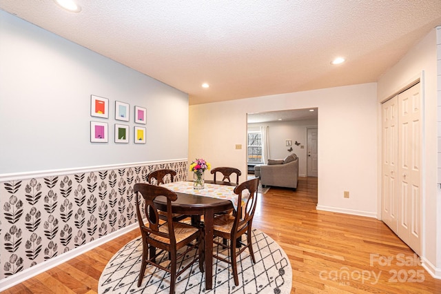 dining area featuring wallpapered walls, light wood-style flooring, a textured ceiling, and recessed lighting