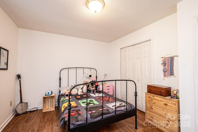 bedroom with a closet, dark wood finished floors, a textured ceiling, and baseboards