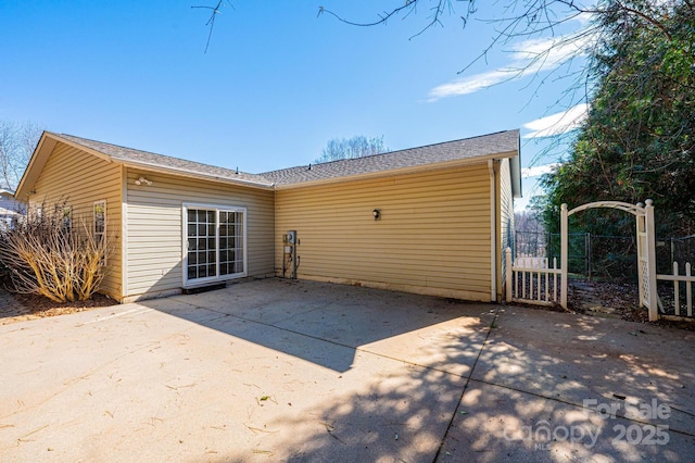 rear view of property with a gate, a patio, and fence