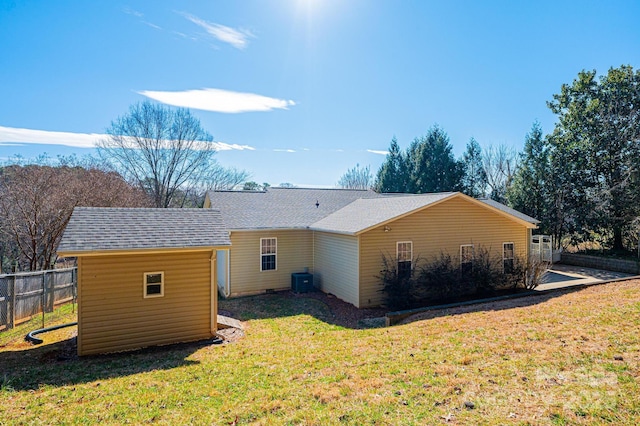 back of property with a lawn and fence