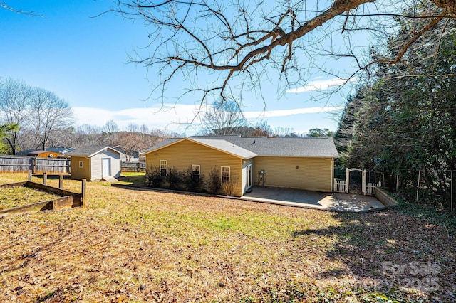 exterior space featuring an outbuilding, a vegetable garden, a storage unit, a lawn, and a patio area