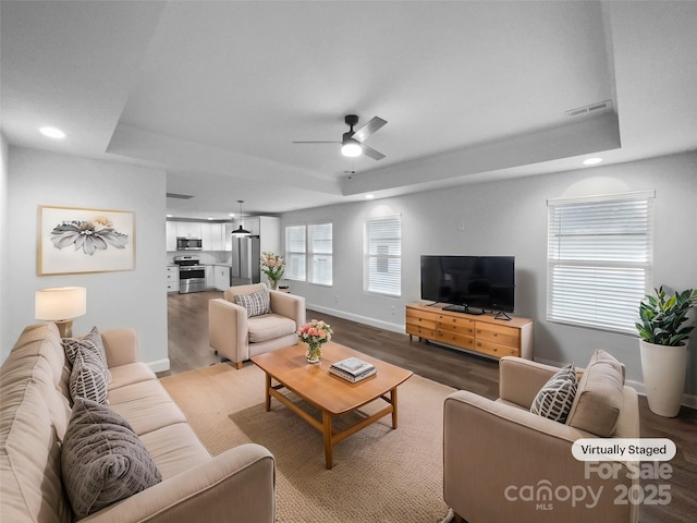 living room featuring ceiling fan, recessed lighting, wood finished floors, baseboards, and a raised ceiling