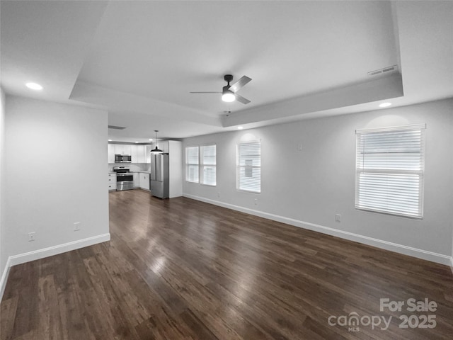 unfurnished living room featuring ceiling fan, recessed lighting, dark wood-style flooring, baseboards, and a raised ceiling