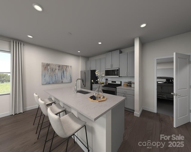 kitchen featuring stainless steel appliances, a sink, a kitchen breakfast bar, decorative backsplash, and dark wood-style floors