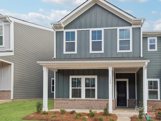 view of front of home featuring covered porch, board and batten siding, and brick siding