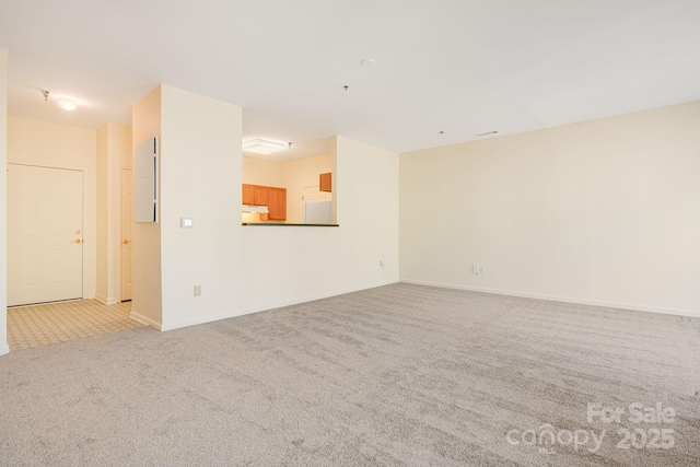 unfurnished living room with baseboards and light colored carpet