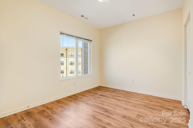 empty room with light wood-type flooring, baseboards, and visible vents