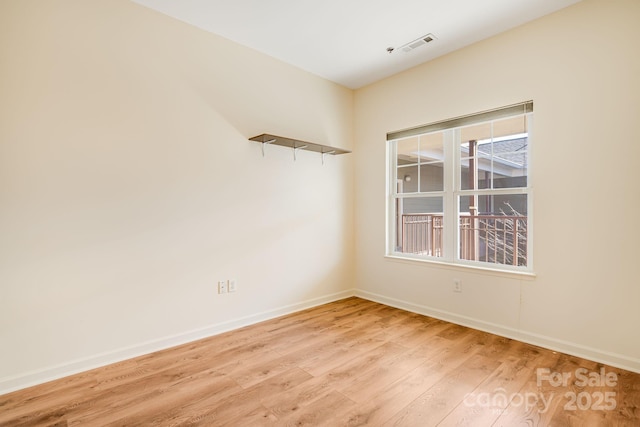 spare room with light wood finished floors, baseboards, and visible vents