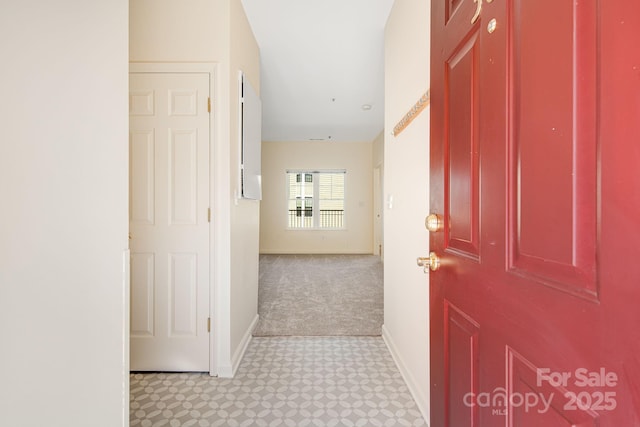 hall with carpet, baseboards, and tile patterned floors