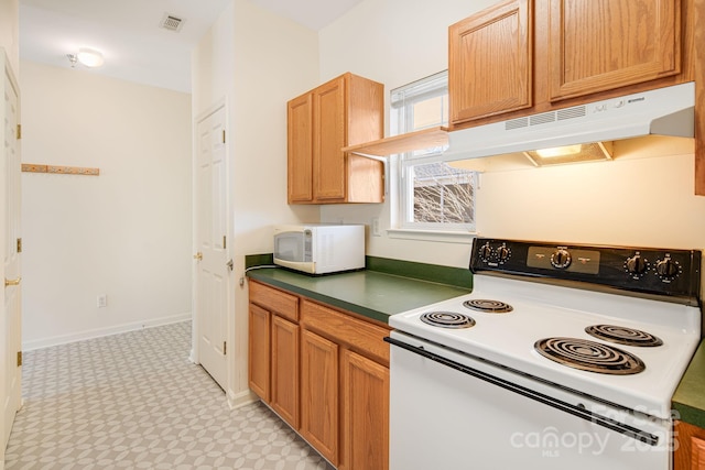 kitchen featuring white appliances, baseboards, visible vents, dark countertops, and under cabinet range hood