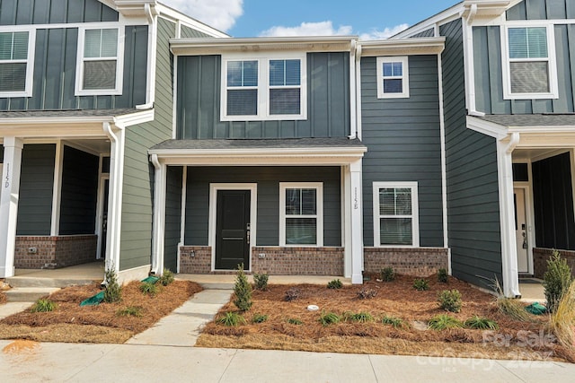 view of front of house with board and batten siding, brick siding, and a porch