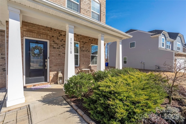 entrance to property featuring covered porch and brick siding