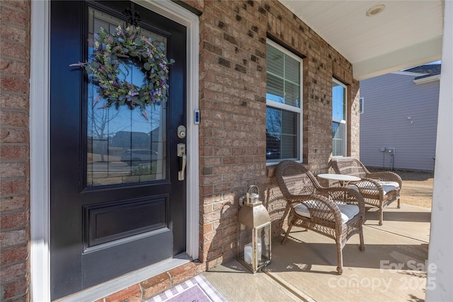 entrance to property with covered porch and brick siding