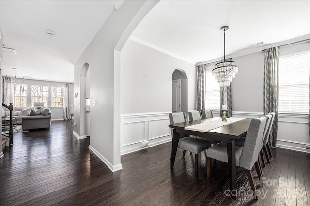 dining space featuring crown molding, visible vents, dark wood finished floors, and arched walkways