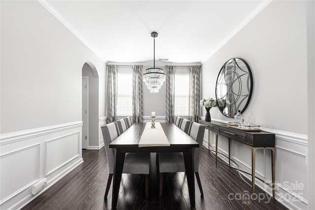 dining room featuring ornamental molding, arched walkways, and dark wood-style floors