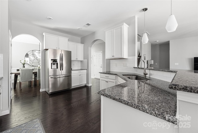 kitchen with dark wood-type flooring, a sink, white cabinetry, stainless steel refrigerator with ice dispenser, and dark stone countertops