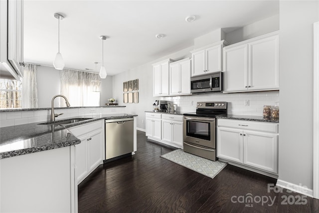 kitchen with stainless steel appliances, a sink, white cabinetry, backsplash, and dark wood finished floors