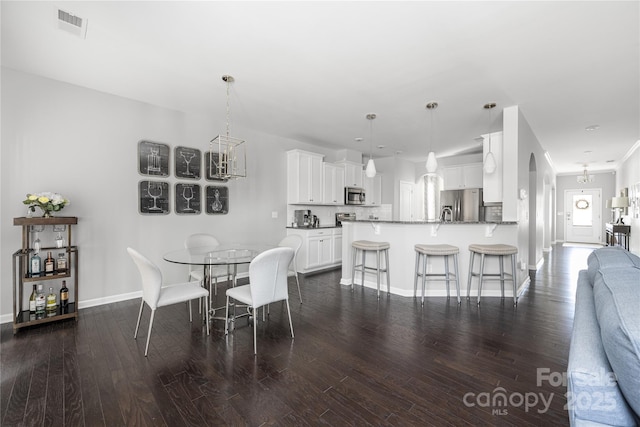 dining area with dark wood-type flooring, visible vents, and baseboards