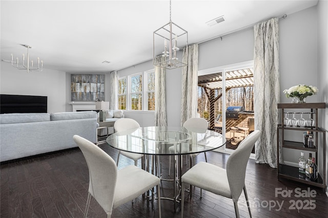 dining space with visible vents, hardwood / wood-style flooring, and a notable chandelier