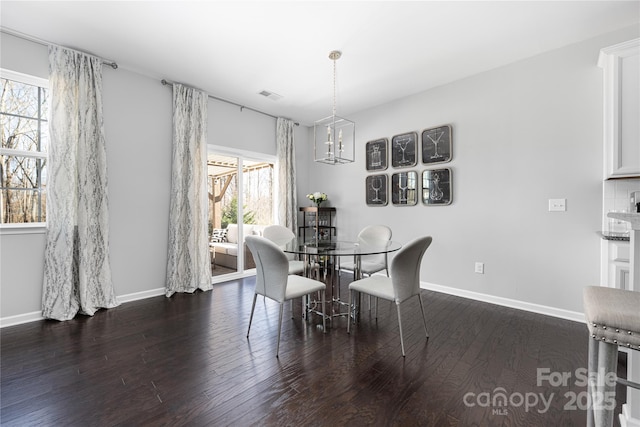 dining area with a notable chandelier, visible vents, baseboards, and wood finished floors