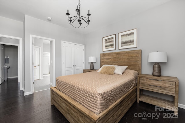 bedroom featuring baseboards, connected bathroom, dark wood-type flooring, a chandelier, and a closet