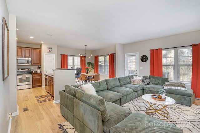 living area featuring light wood-style floors, recessed lighting, visible vents, and a notable chandelier