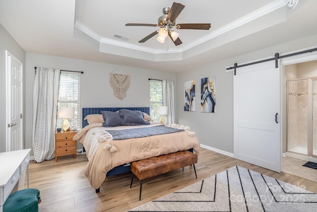 bedroom featuring a raised ceiling, visible vents, multiple windows, and a barn door