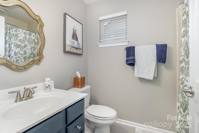 bathroom with toilet, vanity, and baseboards