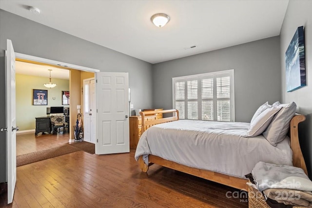 bedroom with hardwood / wood-style flooring, visible vents, and lofted ceiling