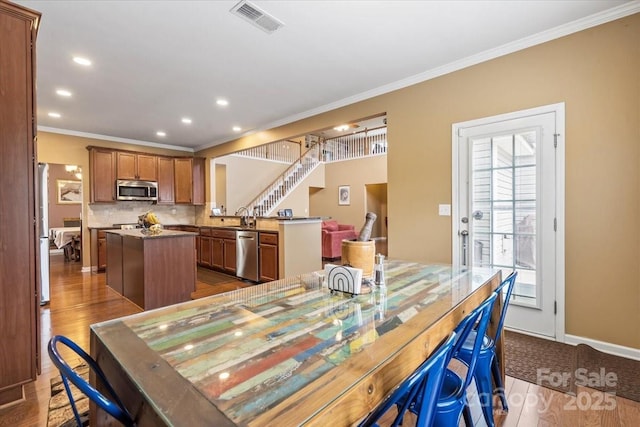 dining area featuring baseboards, visible vents, ornamental molding, stairs, and dark wood-type flooring