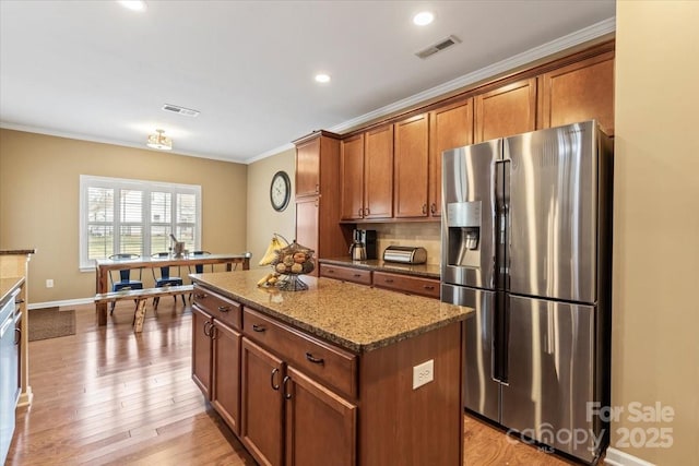 kitchen with visible vents, stone countertops, a kitchen island, appliances with stainless steel finishes, and crown molding