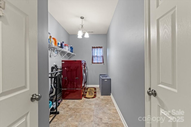 washroom with laundry area, baseboards, a chandelier, and washing machine and clothes dryer