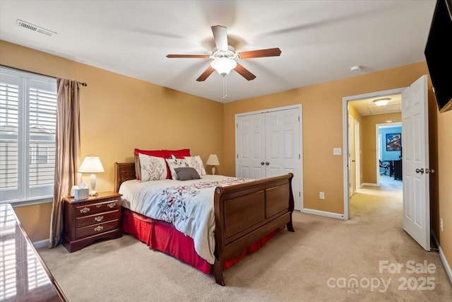 bedroom with visible vents, baseboards, light carpet, a closet, and a ceiling fan