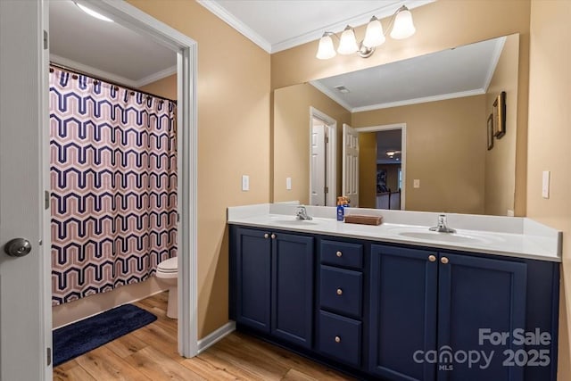 bathroom featuring a sink, double vanity, wood finished floors, and crown molding