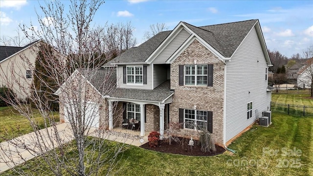 traditional-style home featuring a front yard, fence, a shingled roof, a patio area, and brick siding