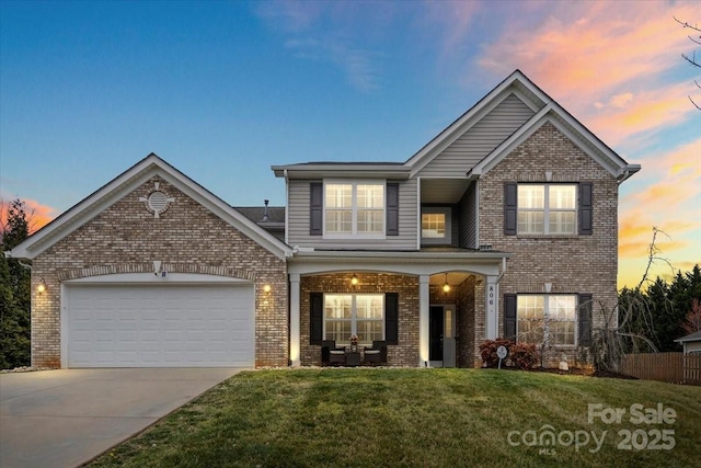 view of front of house with a lawn, fence, concrete driveway, an attached garage, and brick siding