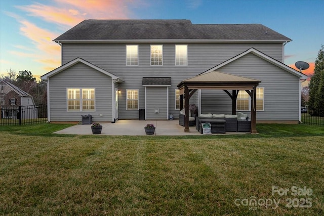 back of property at dusk with a patio, fence, a yard, a gazebo, and outdoor lounge area