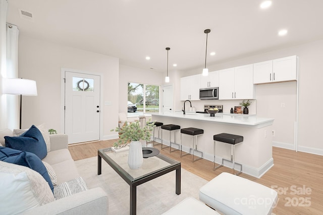 living room featuring baseboards, light wood-type flooring, and recessed lighting