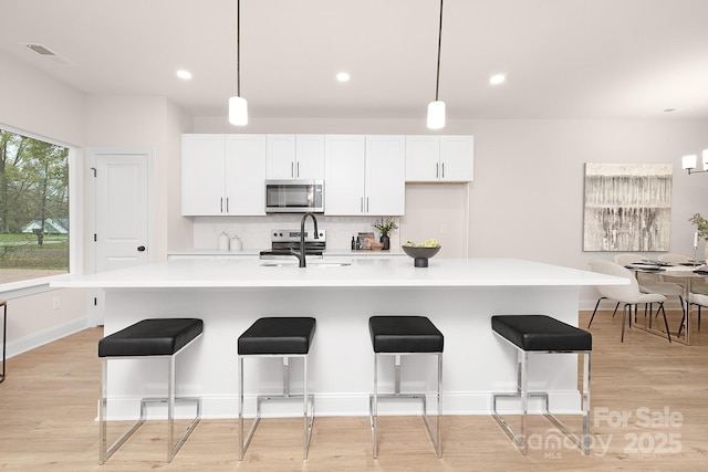 kitchen with light countertops, visible vents, decorative backsplash, appliances with stainless steel finishes, and a sink