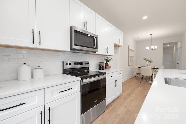 kitchen featuring tasteful backsplash, light wood-style flooring, stainless steel appliances, light countertops, and white cabinetry