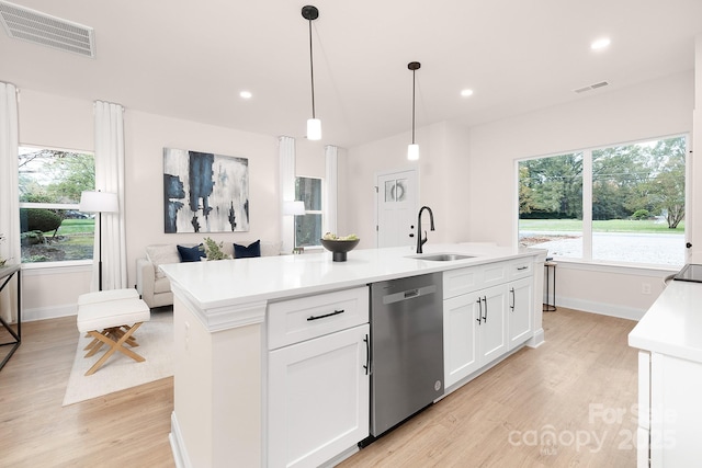 kitchen with visible vents, stainless steel dishwasher, a kitchen island with sink, white cabinets, and a sink