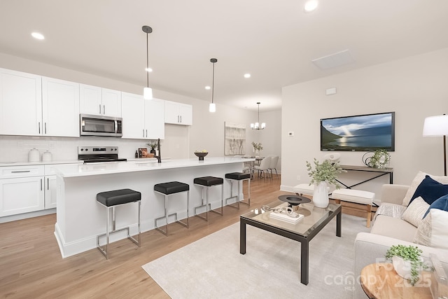 living area with light wood-type flooring, a chandelier, and recessed lighting