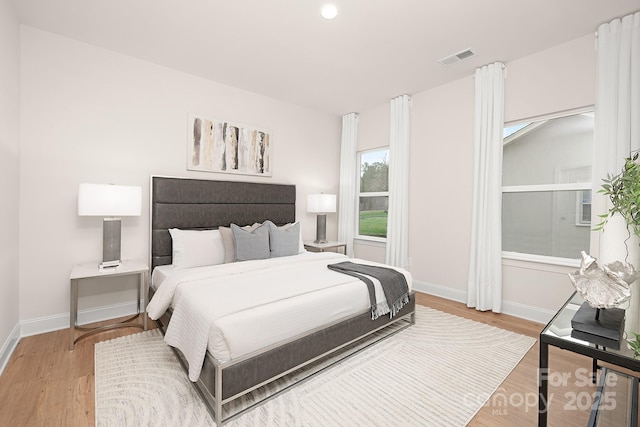 bedroom with light wood-style floors, baseboards, and visible vents