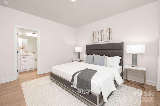 bedroom featuring connected bathroom, light wood-style flooring, and baseboards