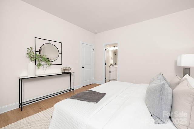 bedroom featuring ensuite bathroom, baseboards, and wood finished floors