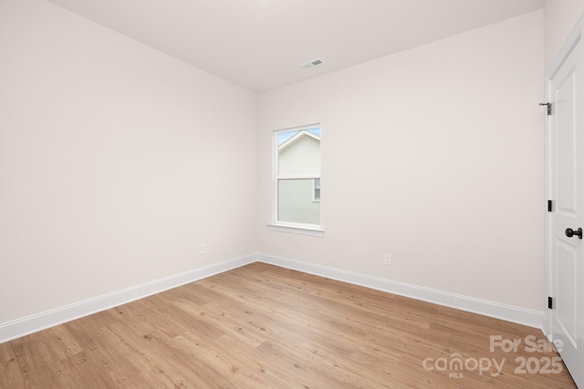 spare room featuring light wood finished floors, baseboards, and visible vents